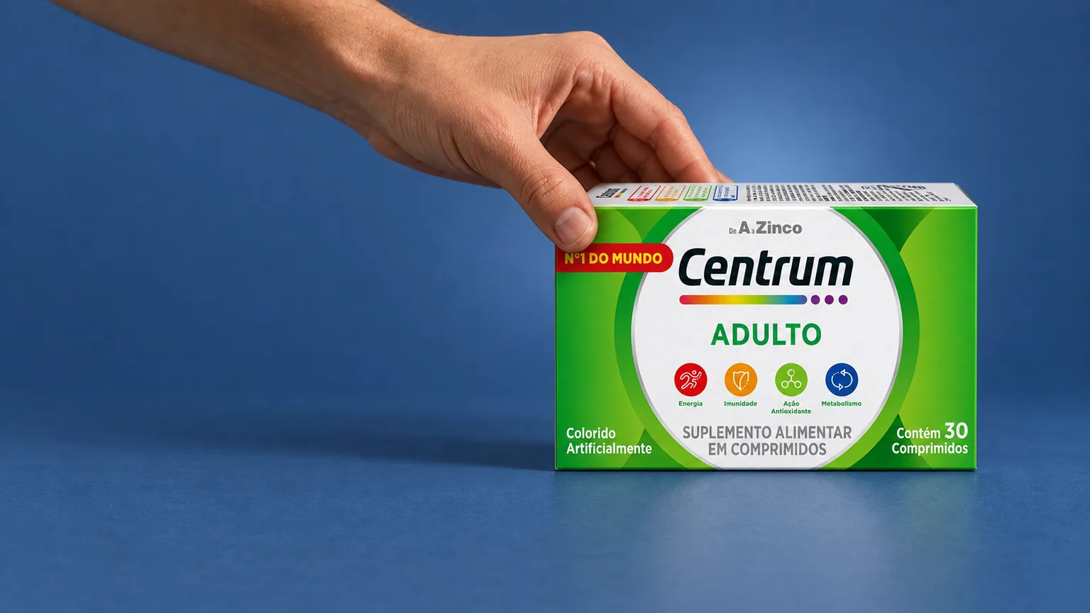 Mão segura uma caixa de Centrum Adulto sobre fundo azul, em capa sobre avaliação do uso de suplementos.